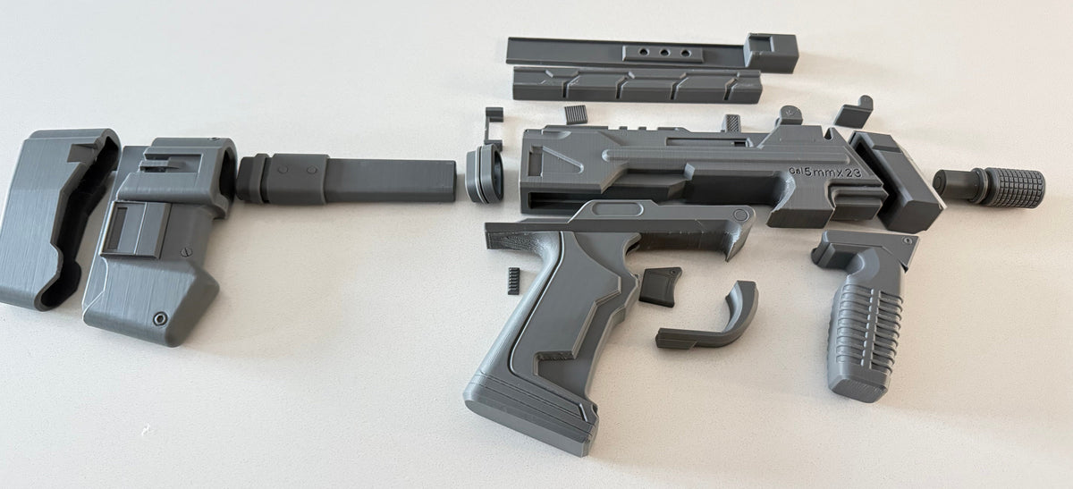 M7 Caseless SMG prop kit parts flat-lay showing receiver, stock, grips, magazine and rail sections