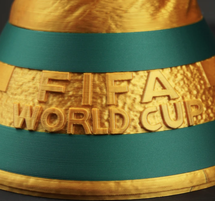 Close-up of a FIFA World Cup trophy with gold and green bands.| 3dCre8Design