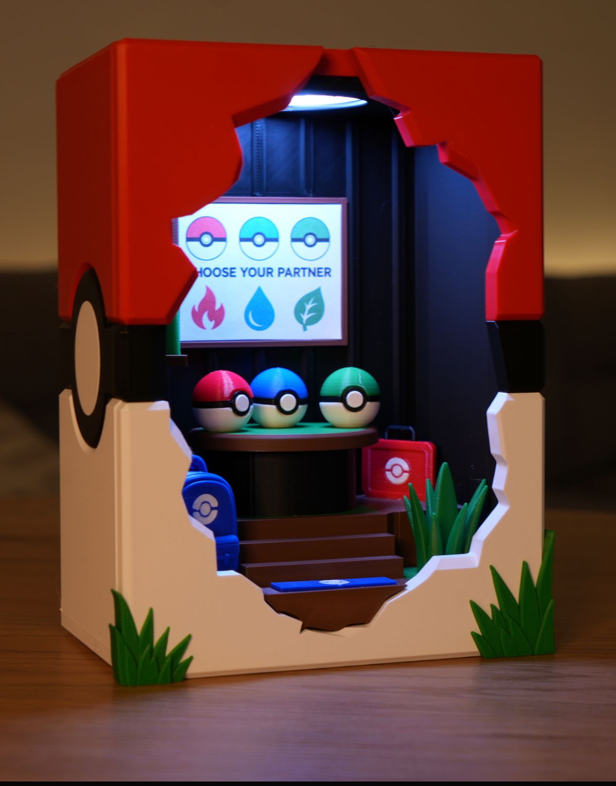 Broken Brick LED lamp lit up in a dark room, showing the glowing Choose Your Partner sign and the Fire, Water and Grass Poké Balls inside