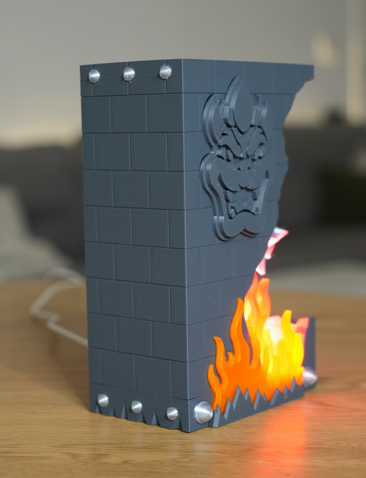 Broken Brick Bowser LED night light, lit version glowing red and orange, rear-angled view on a desk